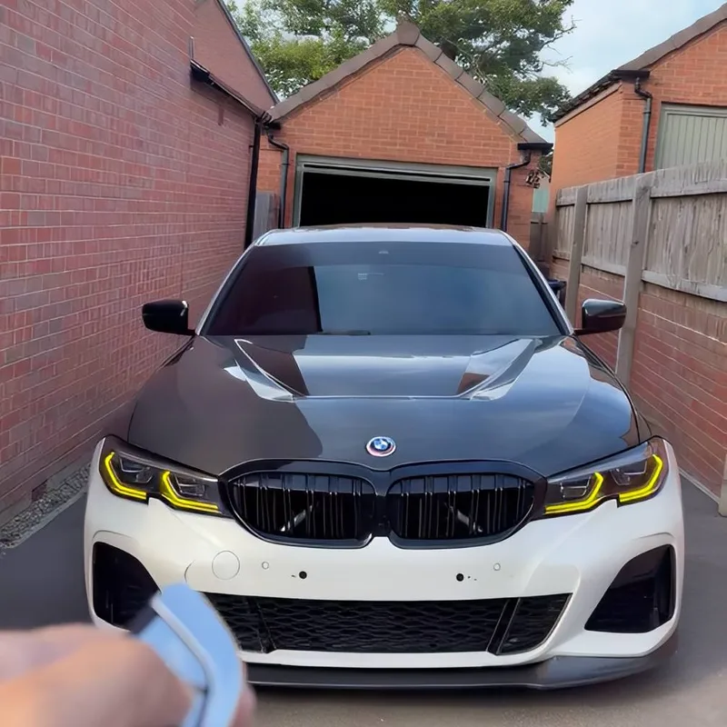 A white BMW G20 M340i with a carbon bonnet, its key fob held up in front of it